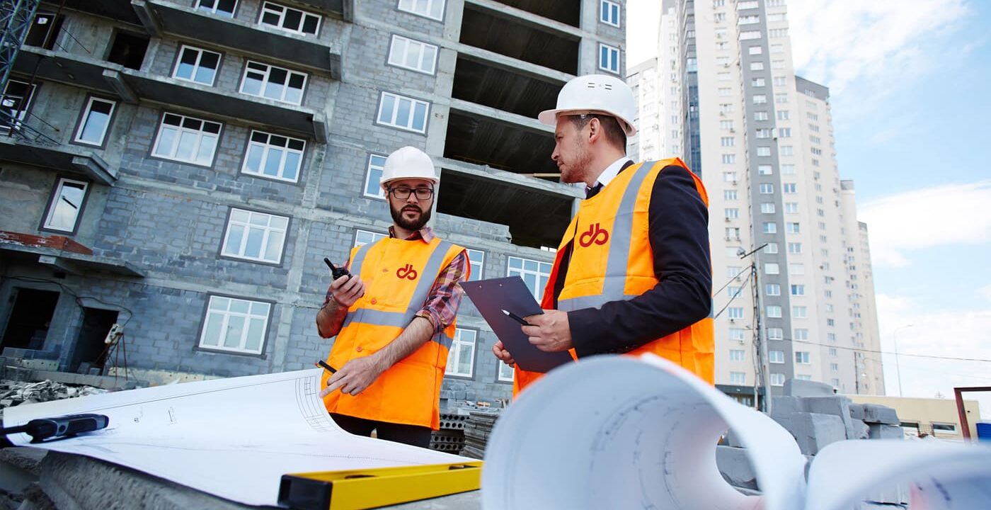 Tecnici di Del Bono S.p.A. in cantiere consultano elaborati tecnici durante la verifica di un intervento edilizio.